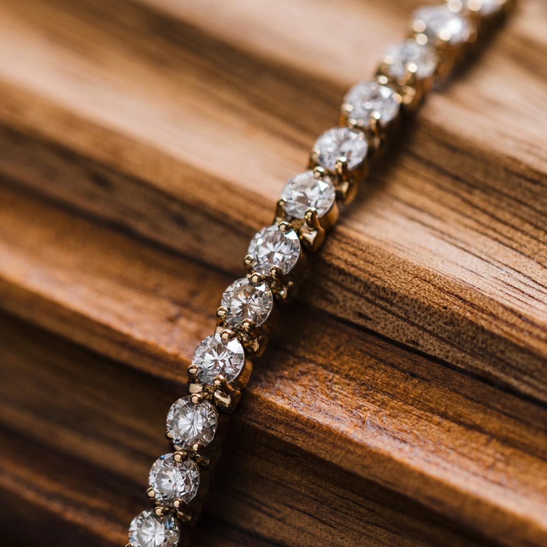 Diamond bracelet laying across curved wooden background